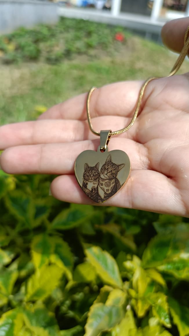 Collar dorado en forma de corazón con dos gatos grabados